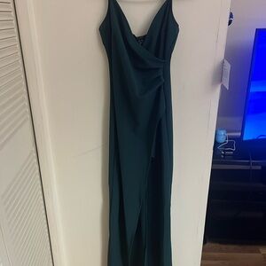 Dark green Windsor HOCO dress, has a thigh slit on left leg and is long.